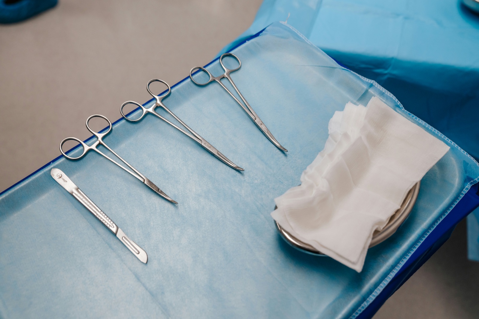 Stainless surgical forceps and scalpel on blue drape for Epo-Weld™ UHB ultra high bond epoxy medical device bonding