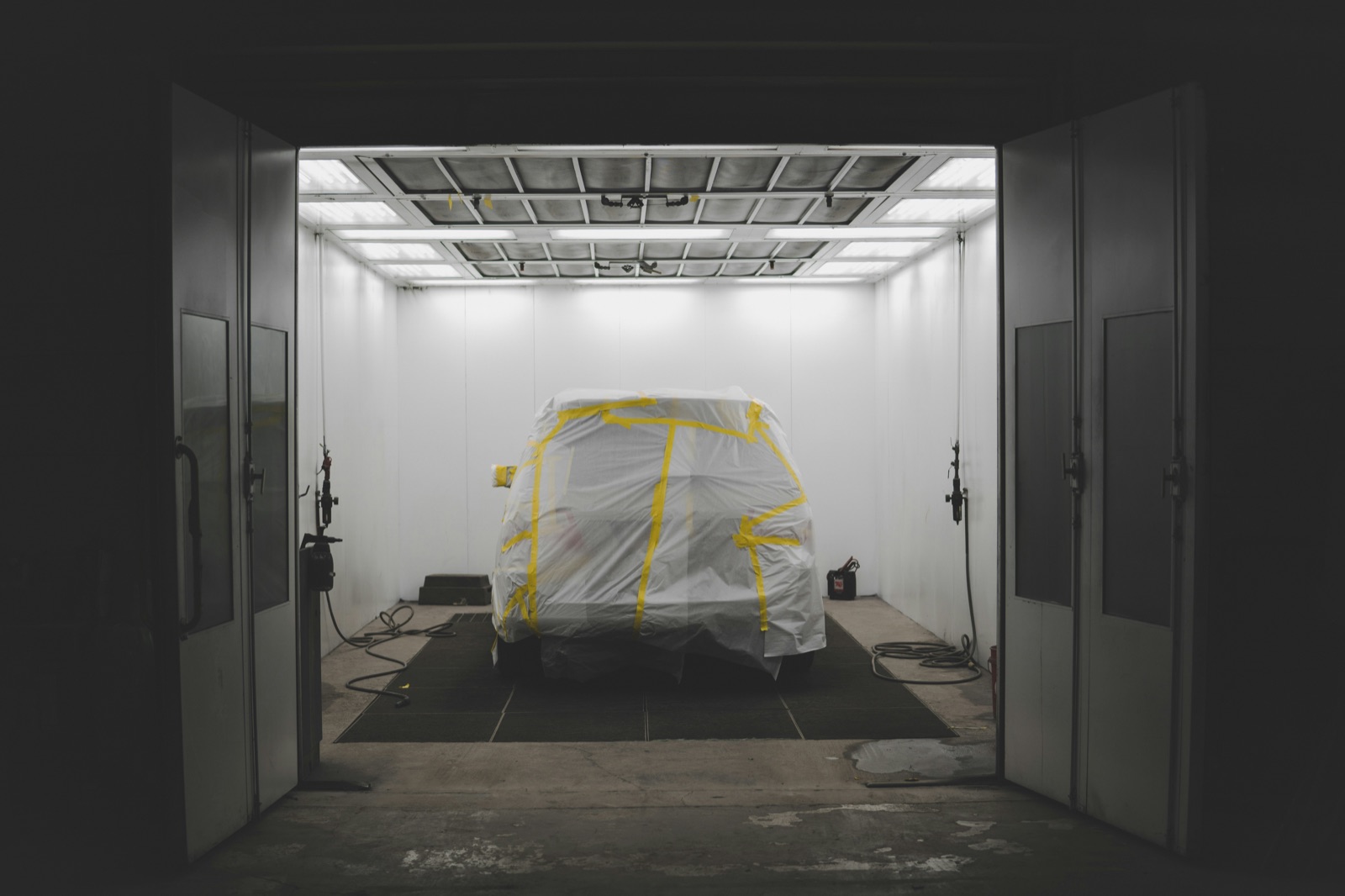 Vehicle fully masked with protective sheeting in industrial paint booth for Pyra-Sil™ powder coat masking