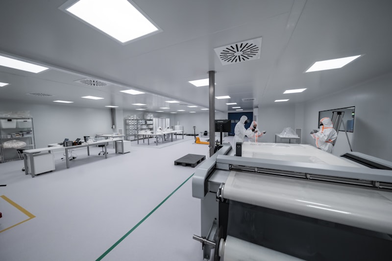 Technicians in full protective suits working in ISO cleanroom for Optik™ UV camera module active alignment assembly
