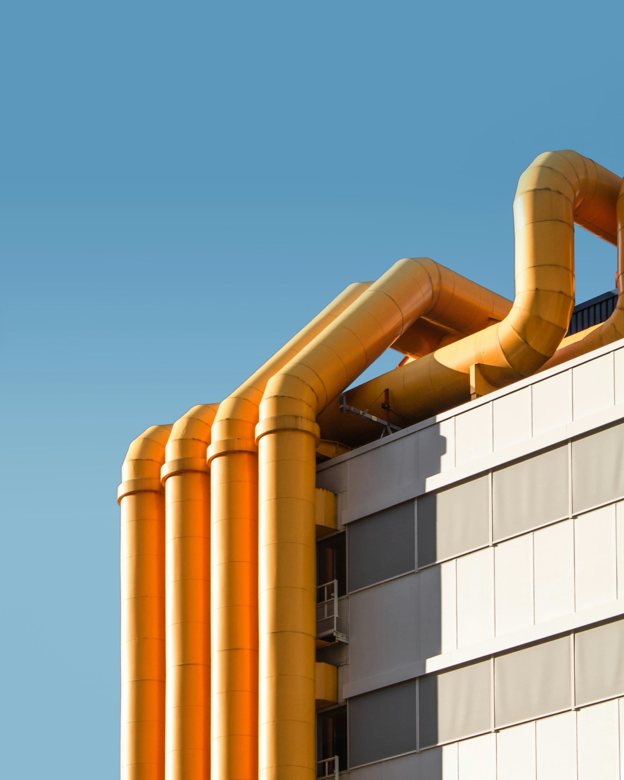 Large yellow industrial pipes on building exterior for Pyra-Sil™ UV silicone automotive and industrial sealing